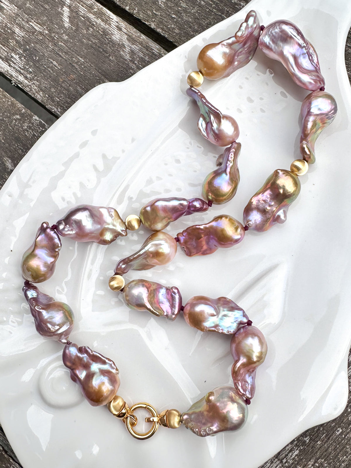 Necklace with pink and gold baroque freshwater pearls on a white dish