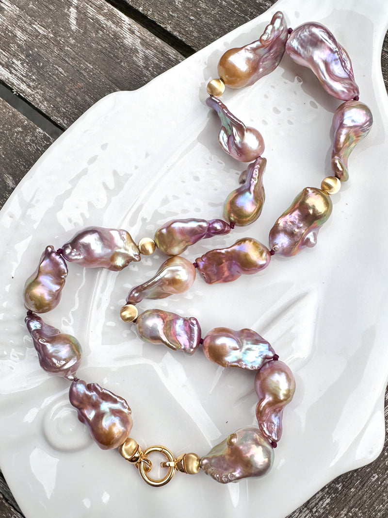 Necklace with pink and gold baroque freshwater pearls on a white dish