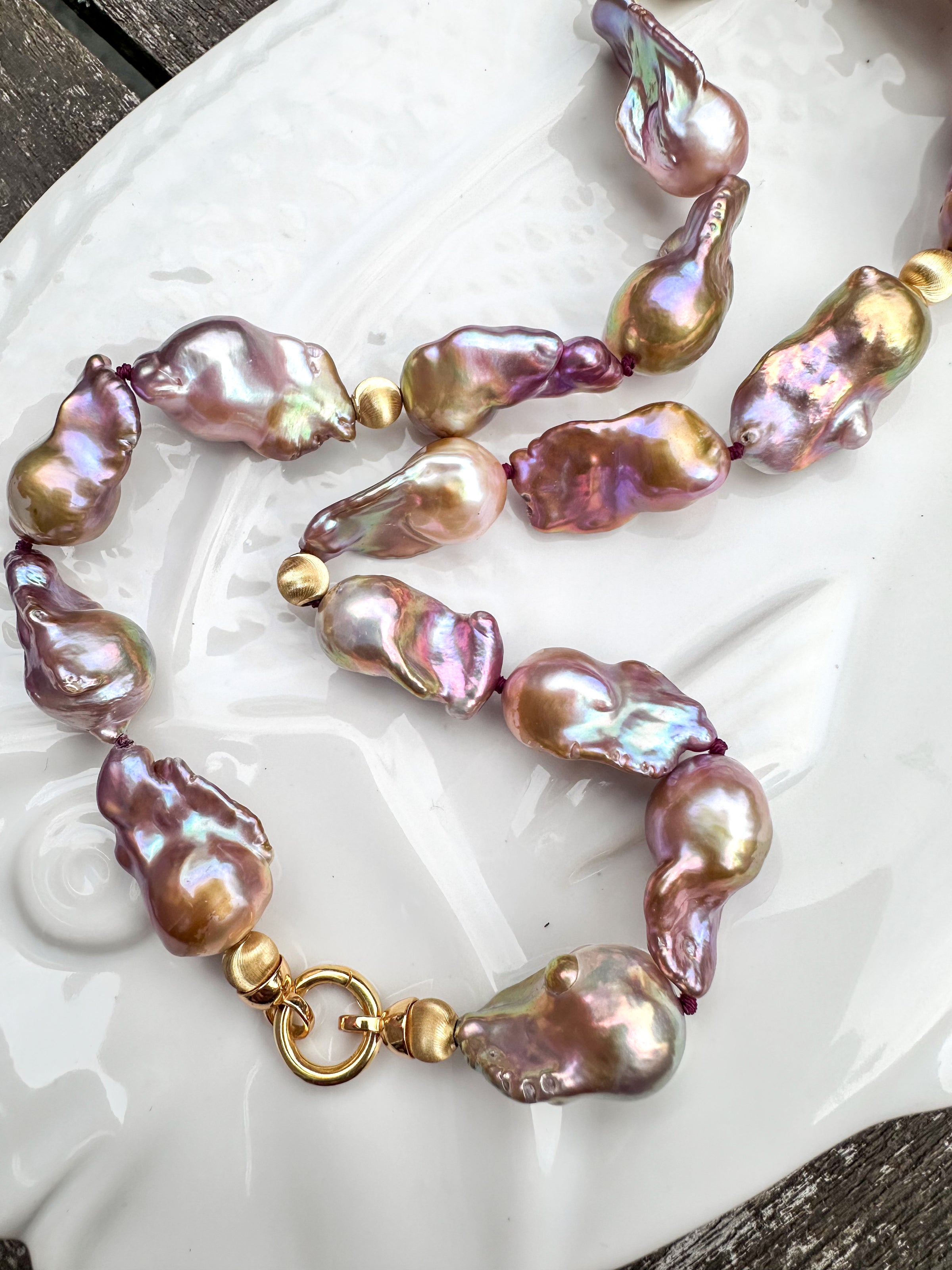 Necklace with pink and gold baroque freshwater pearls on a white dish