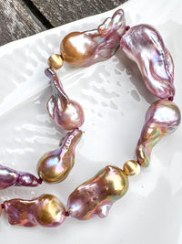 Necklace with pink and gold baroque freshwater pearls on a white dish